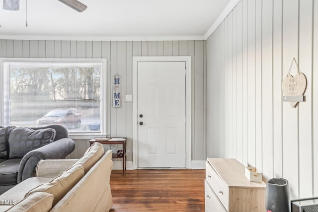 living room with ceiling fan, wood walls, dark hardwood / wood-style flooring, and crown molding