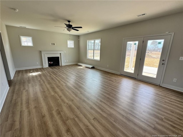 unfurnished living room featuring baseboards, visible vents, a ceiling fan, wood finished floors, and a fireplace