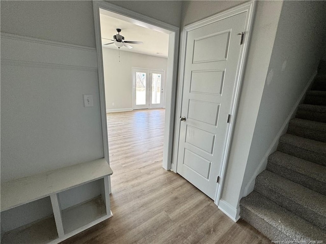 stairway with wood finished floors, a ceiling fan, and baseboards