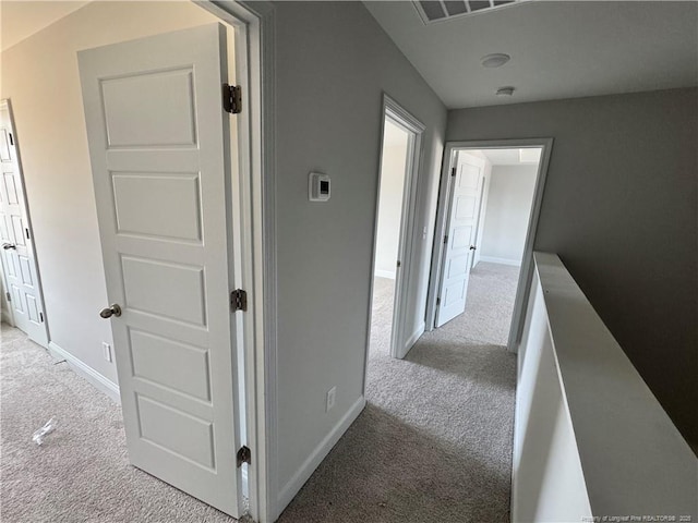 hallway featuring carpet floors, visible vents, and baseboards