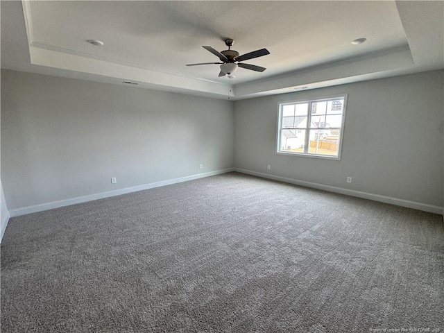 unfurnished room with carpet, baseboards, a tray ceiling, and ceiling fan