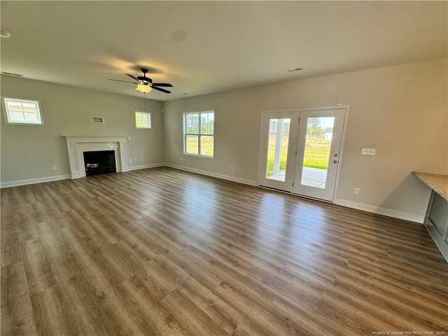 unfurnished living room featuring ceiling fan, wood finished floors, and baseboards