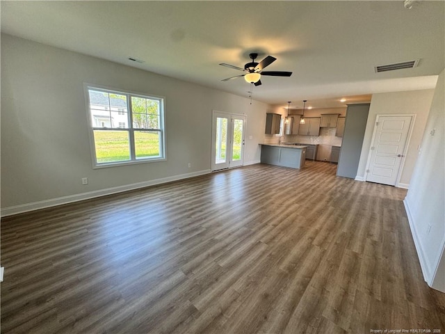 unfurnished living room with visible vents, dark wood-style flooring, baseboards, and ceiling fan