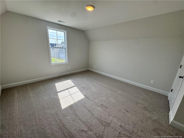 additional living space featuring carpet flooring, baseboards, and vaulted ceiling