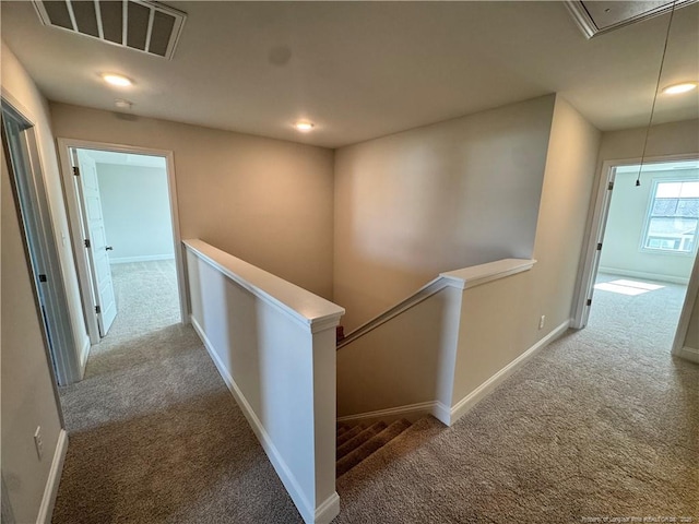 corridor with carpet flooring, an upstairs landing, attic access, and visible vents