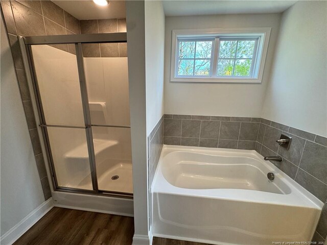 bathroom featuring a garden tub, a stall shower, and wood finished floors