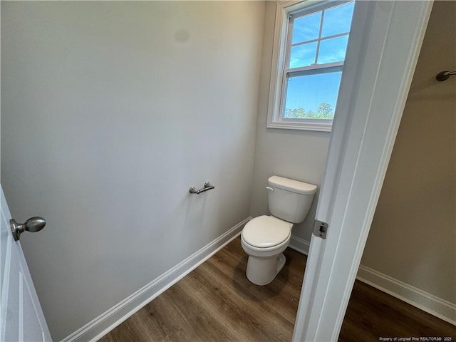 bathroom with toilet, wood finished floors, and baseboards