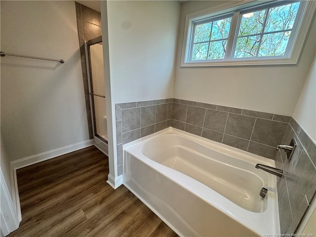 full bathroom with baseboards, a shower stall, wood finished floors, and a garden tub