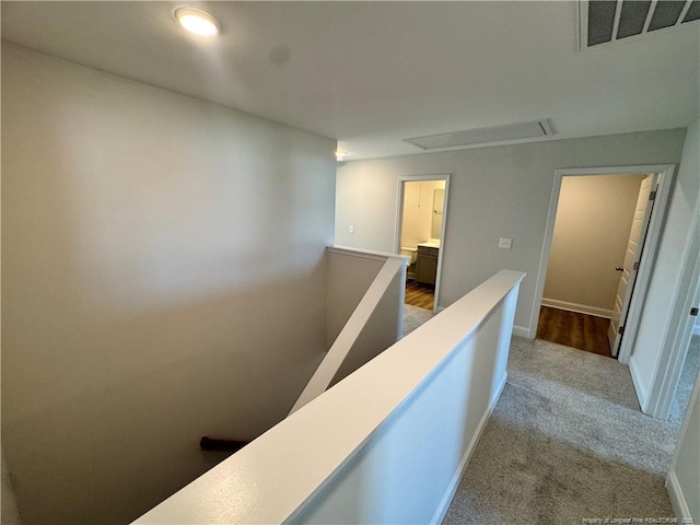 hallway featuring visible vents, carpet floors, attic access, an upstairs landing, and baseboards