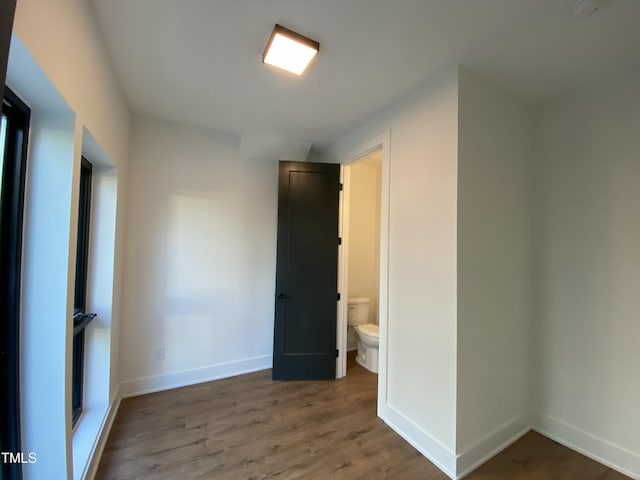 unfurnished bedroom with wood-type flooring and ensuite bath