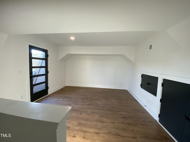 additional living space featuring vaulted ceiling and dark wood-type flooring