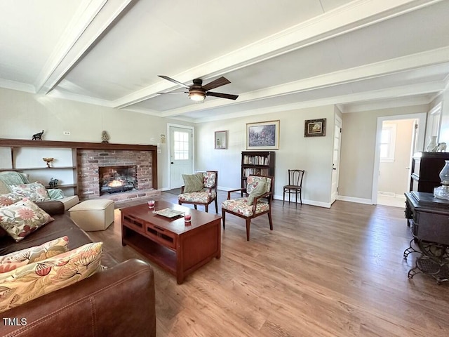 living room with ceiling fan, crown molding, wood-type flooring, beamed ceiling, and a fireplace