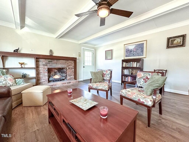 living room featuring beam ceiling, crown molding, a fireplace, and wood-type flooring