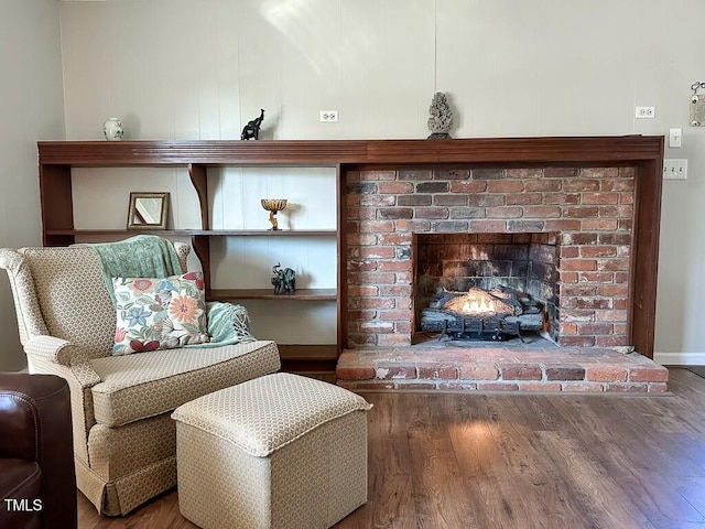 sitting room with wood-type flooring and a brick fireplace