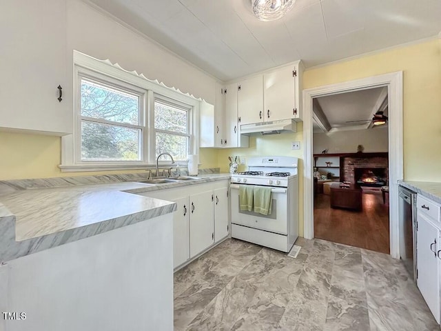 kitchen featuring dishwasher, sink, a brick fireplace, gas range gas stove, and white cabinetry