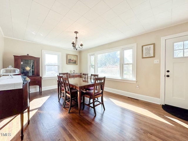 dining area featuring a chandelier, a healthy amount of sunlight, and dark hardwood / wood-style floors