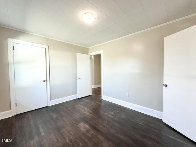 unfurnished bedroom with dark hardwood / wood-style flooring, a closet, and crown molding