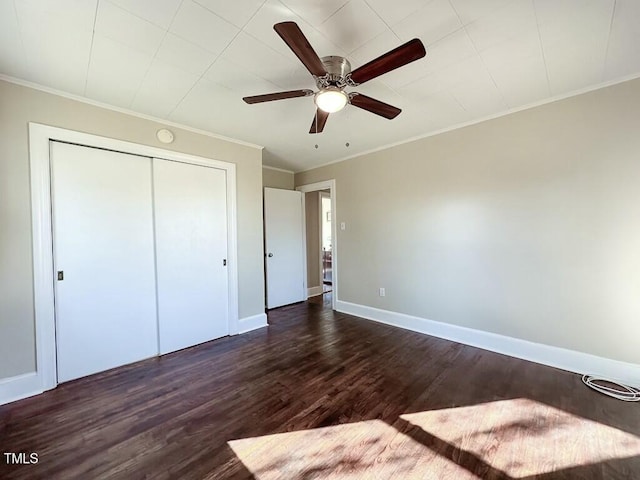 unfurnished bedroom featuring ceiling fan, dark wood-type flooring, crown molding, and a closet