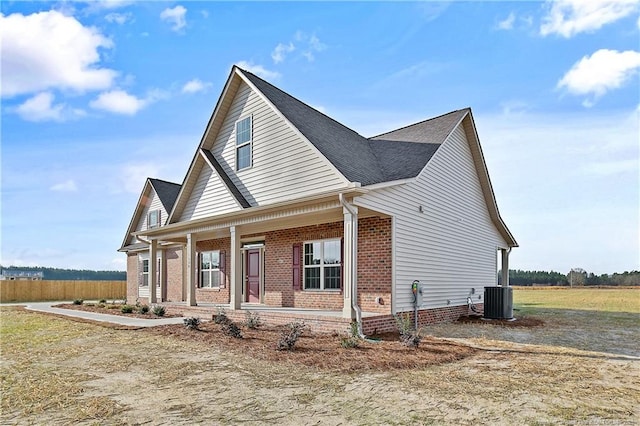 view of front of home featuring covered porch, brick siding, and central air condition unit