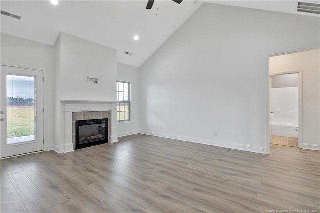 unfurnished living room with high vaulted ceiling, a fireplace, wood finished floors, and visible vents