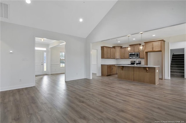 kitchen featuring visible vents, dark wood-style floors, brown cabinets, open floor plan, and stainless steel appliances