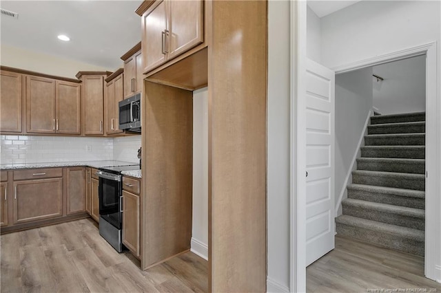 kitchen with light stone countertops, tasteful backsplash, stainless steel appliances, and light wood-style flooring