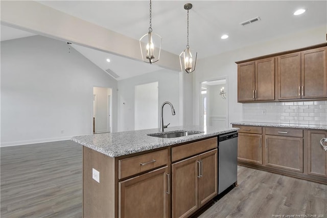 kitchen featuring tasteful backsplash, light wood-style flooring, vaulted ceiling, a sink, and dishwasher