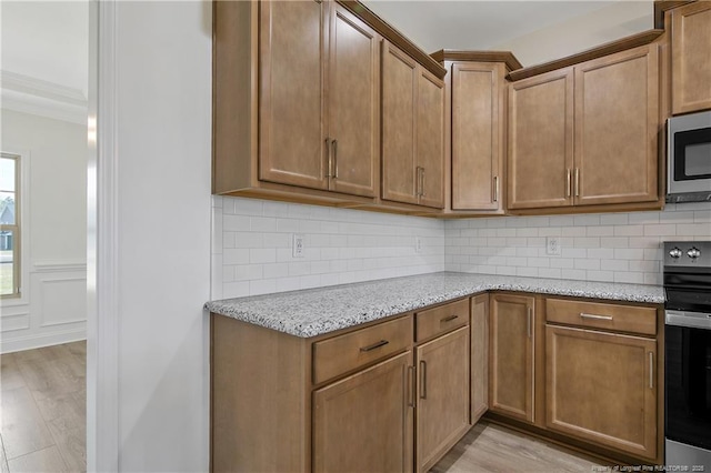 kitchen with light wood-style floors, stainless steel microwave, light stone counters, and electric stove