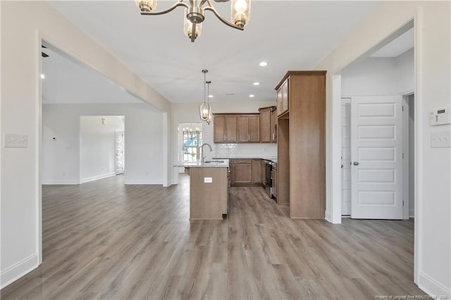 kitchen featuring a sink, light wood-style floors, open floor plan, and a notable chandelier