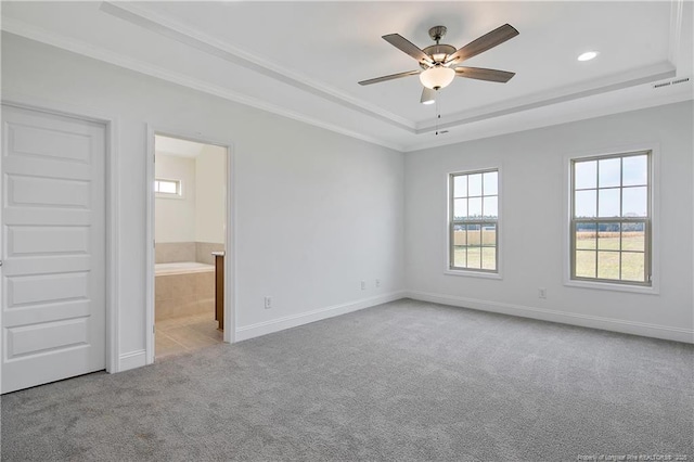 unfurnished bedroom featuring a tray ceiling, carpet flooring, visible vents, and baseboards