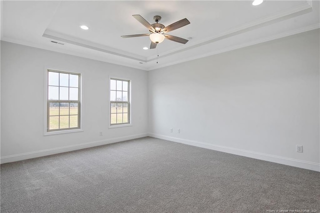 carpeted spare room with visible vents, baseboards, and a raised ceiling