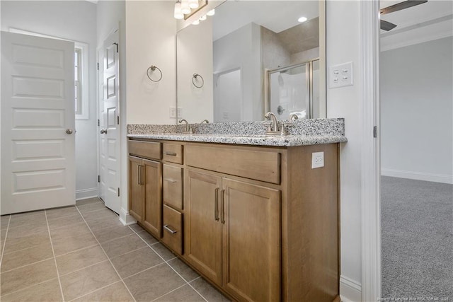 full bath with a stall shower, tile patterned floors, baseboards, and double vanity