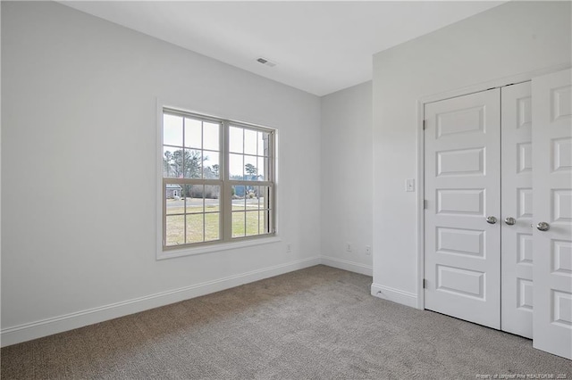 carpeted spare room with visible vents and baseboards