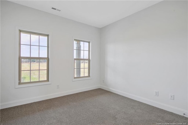 spare room with baseboards, visible vents, and dark colored carpet