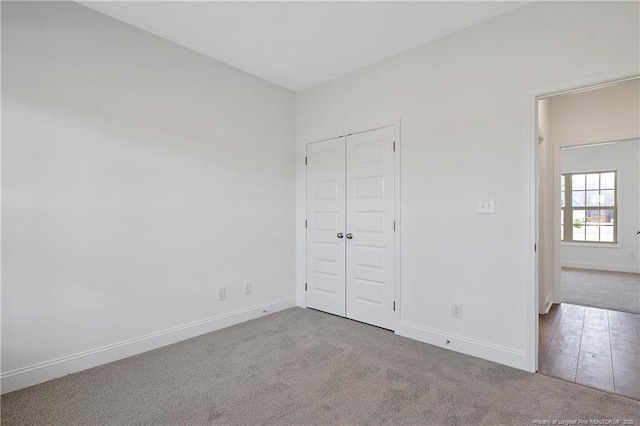 unfurnished bedroom featuring a closet, baseboards, and carpet flooring