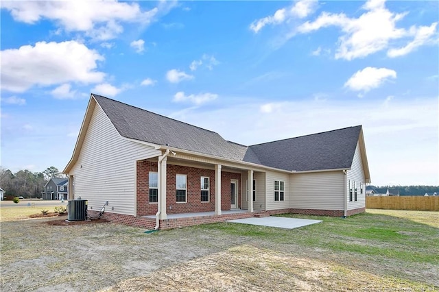 ranch-style home featuring roof with shingles, a front lawn, central AC, and brick siding