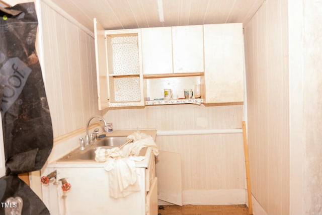 bathroom featuring sink, wooden walls, and wood ceiling