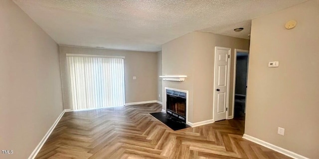 unfurnished living room featuring parquet flooring and a textured ceiling