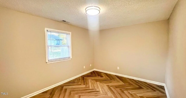 unfurnished room featuring parquet flooring and a textured ceiling