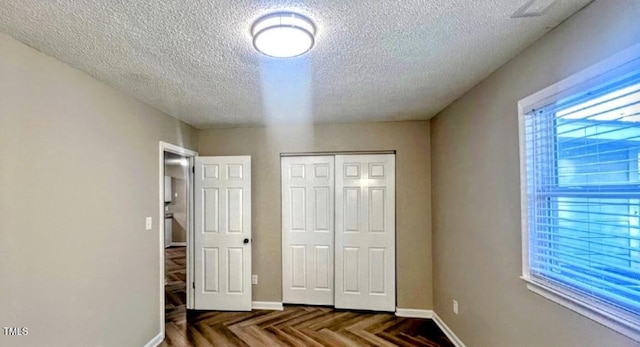 unfurnished bedroom with multiple windows, a textured ceiling, dark parquet floors, and a closet