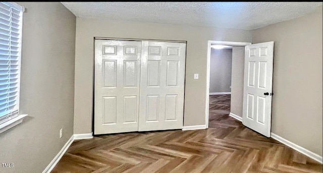 unfurnished bedroom featuring dark parquet floors, a closet, and a textured ceiling