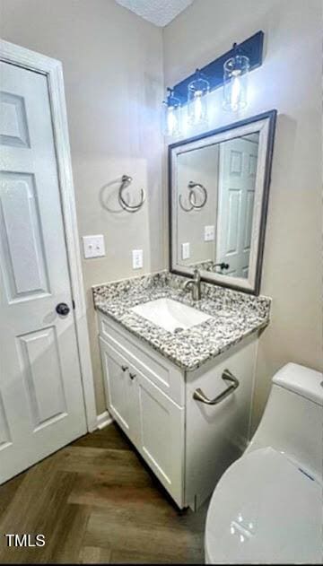 bathroom with vanity, parquet floors, a textured ceiling, and toilet