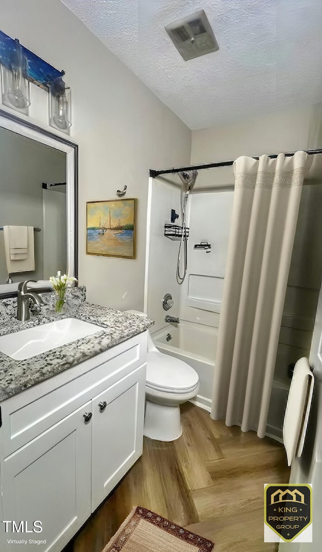 full bathroom featuring shower / bath combo, vanity, a textured ceiling, and toilet