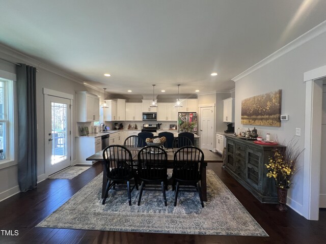 dining area featuring sink, ornamental molding, and dark wood-type flooring