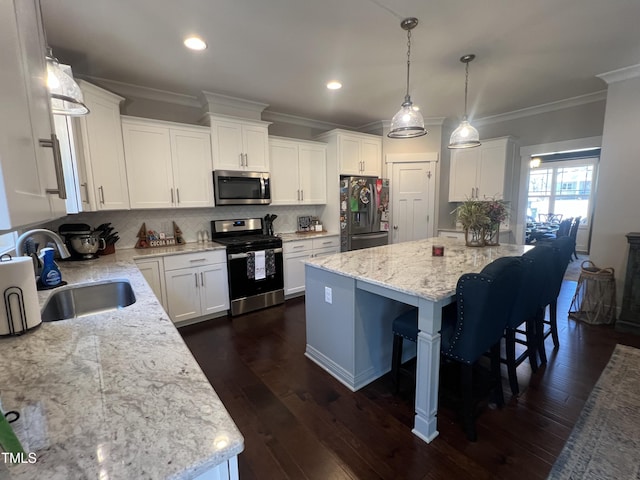 kitchen featuring a center island, sink, hanging light fixtures, stainless steel appliances, and white cabinets