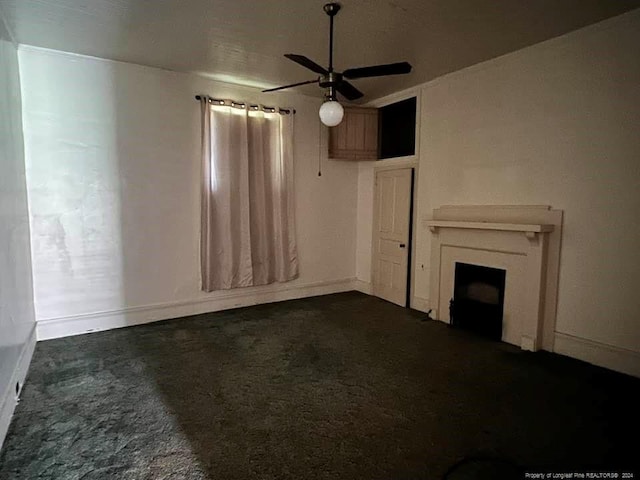 unfurnished living room with ceiling fan and dark carpet