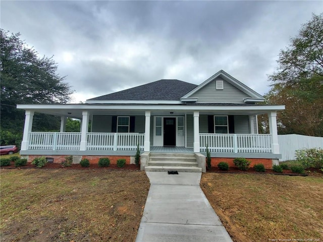 farmhouse with a shingled roof, a front lawn, and a porch