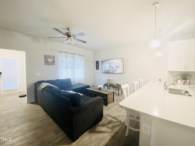 living room with light hardwood / wood-style flooring, ceiling fan, and sink