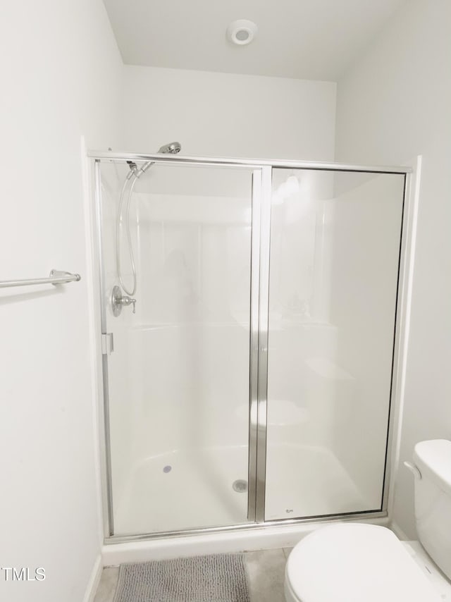 bathroom with toilet and a shower with door