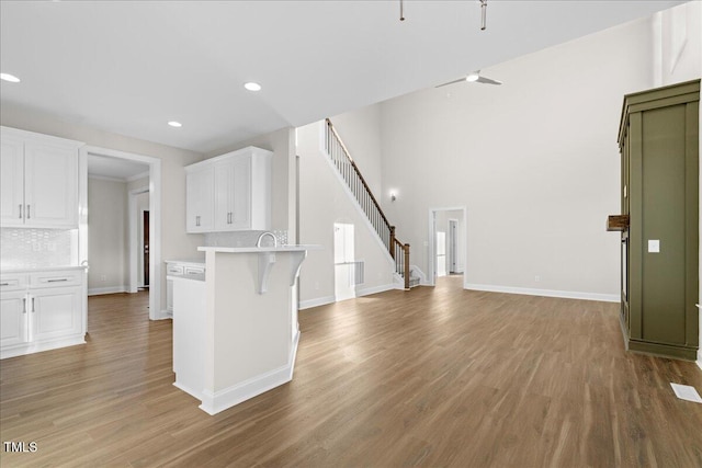 kitchen featuring a breakfast bar, white cabinets, hardwood / wood-style flooring, ceiling fan, and tasteful backsplash